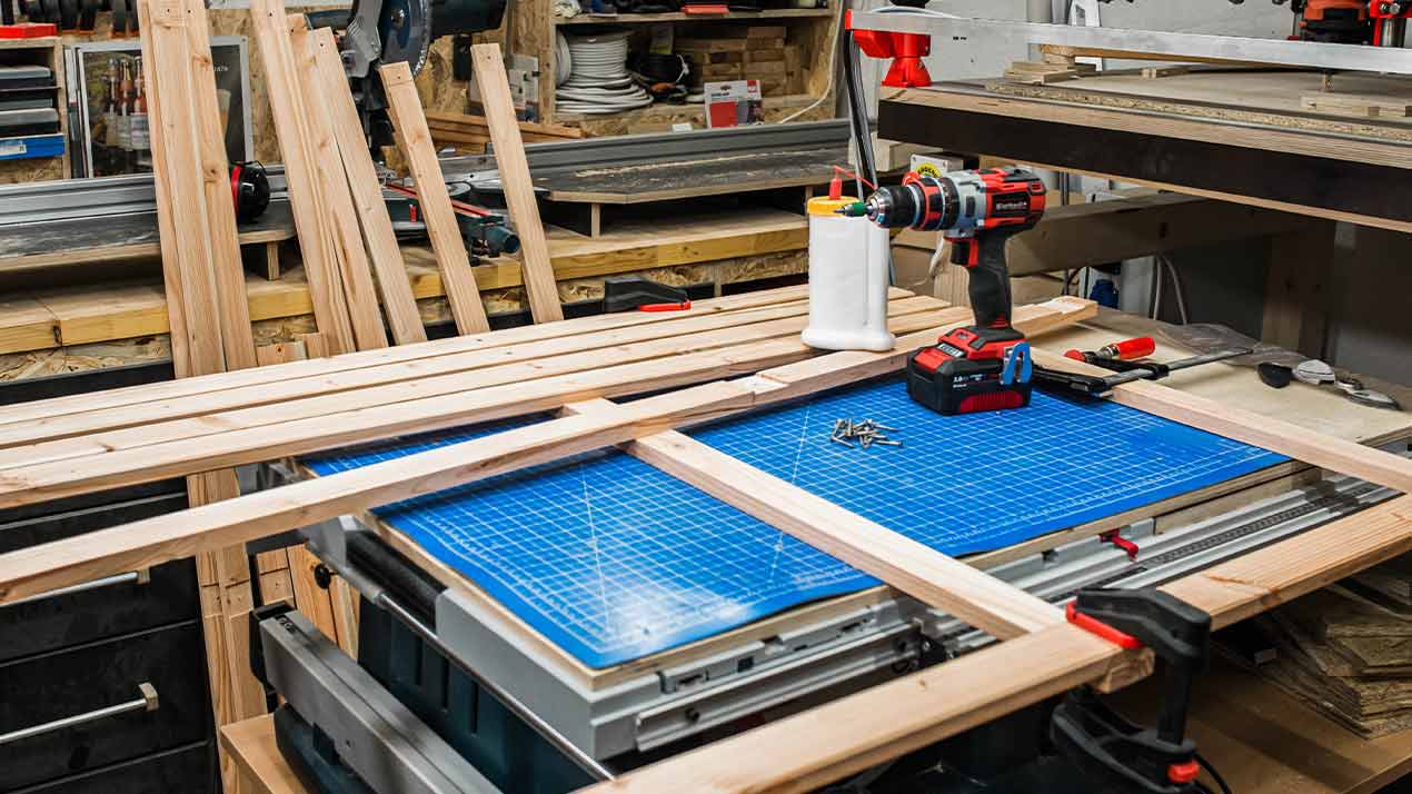 Multiple wooden boards lying on workbench with cordless drill