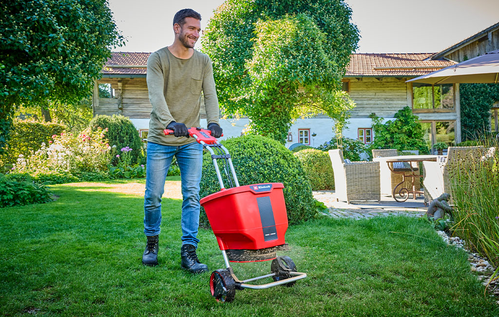 A man fertilises the lawn with the Einhell cordless multi purpose spreader spreader