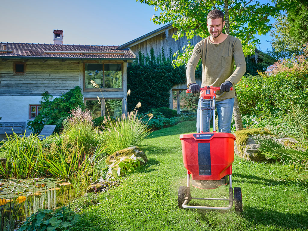 A man fertilises the lawn with the Einhell cordless multi purpose spreader spreader