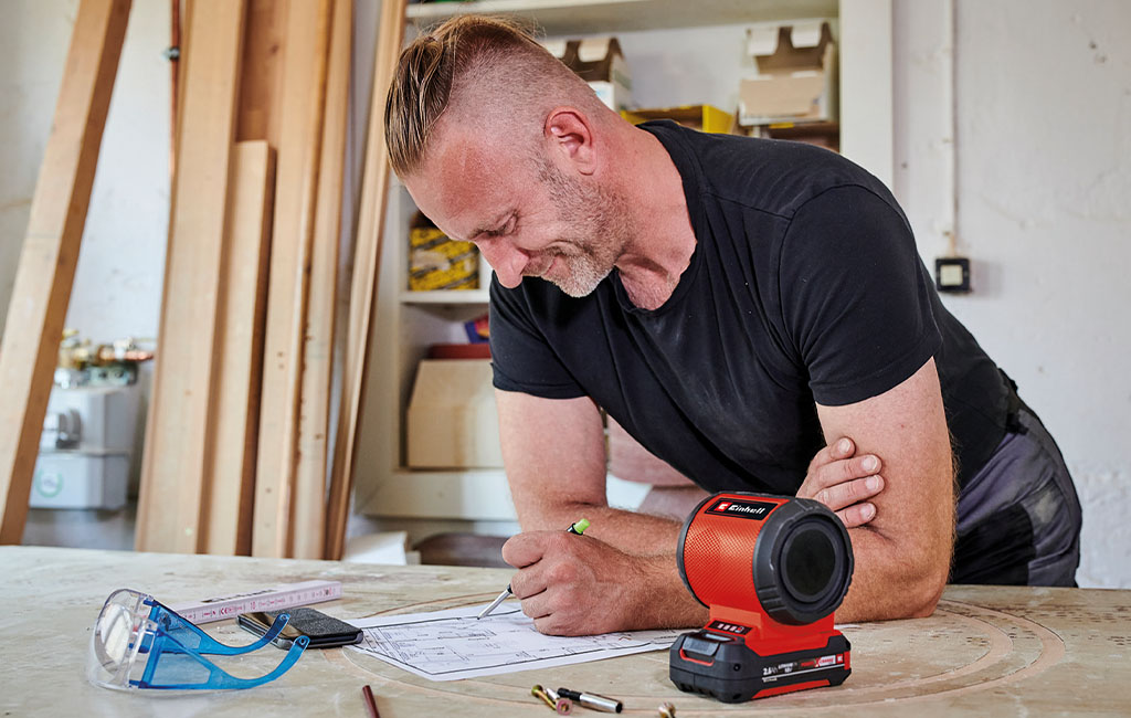 man is listening to music from the Einhell cordless speaker