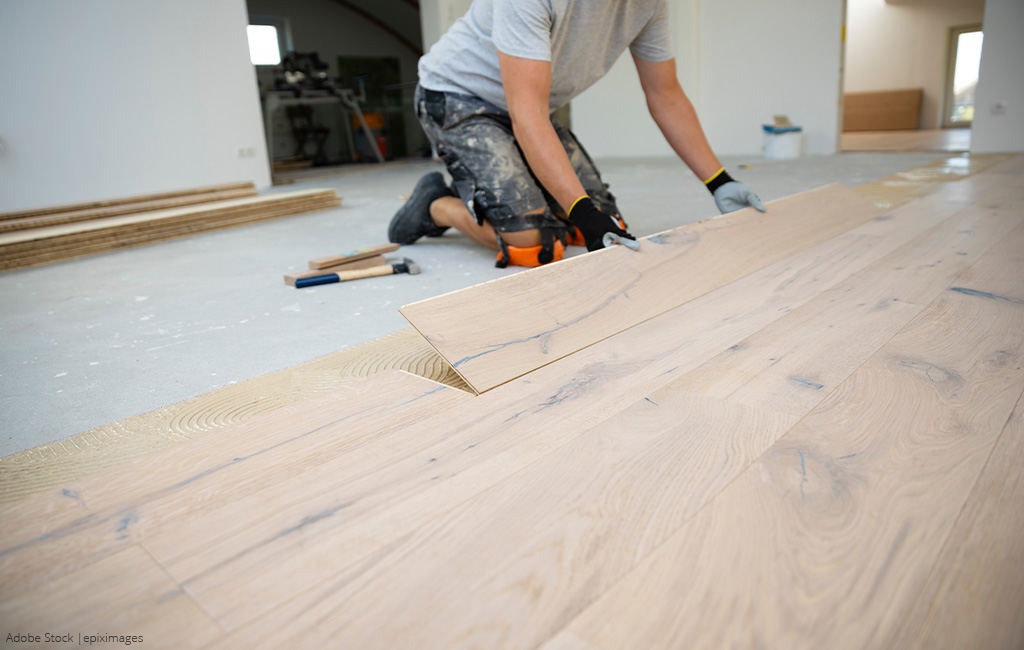 Close-up of a person placing wooden planks on the floor.