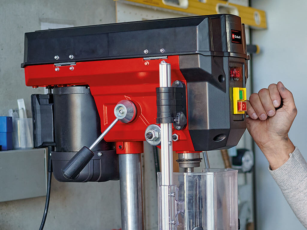 Side view of a bench drill with a lever for adjusting the speed.