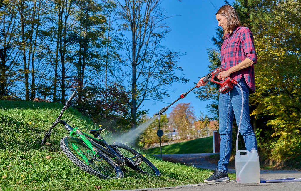 eine Frau reinigt ein Fahrrad mit dem Einhell HYPRESSO