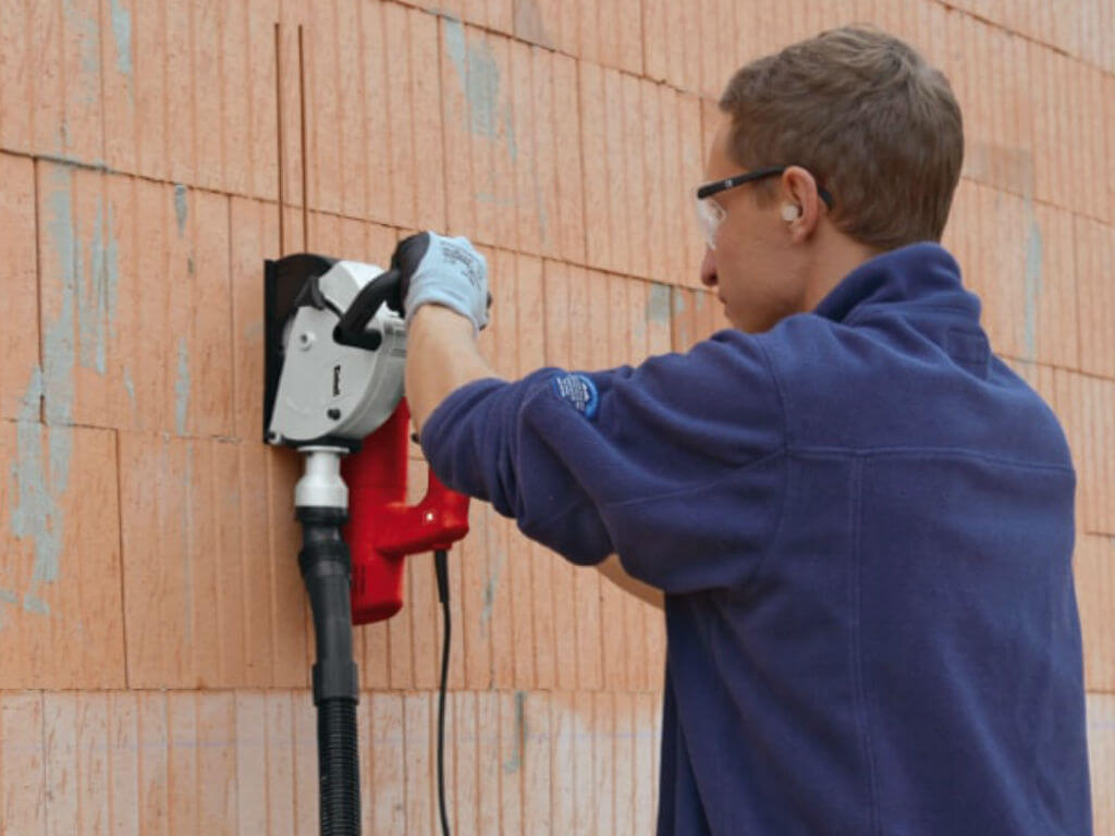 man cuts slits in the wall with a milling machine