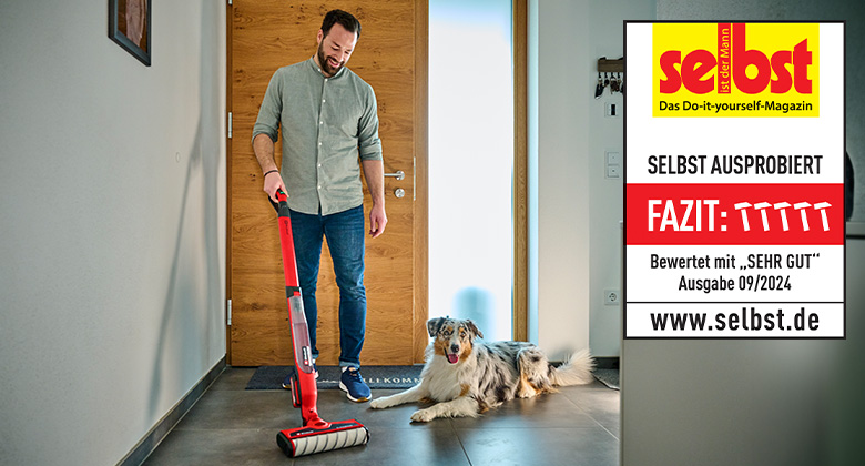 A man uses the Einhell cordless hard floor cleaner CLEANEXXO, rated "Very Good" by "selbst ist der Mann" in issue 09/2024, while a dog sits nearby.