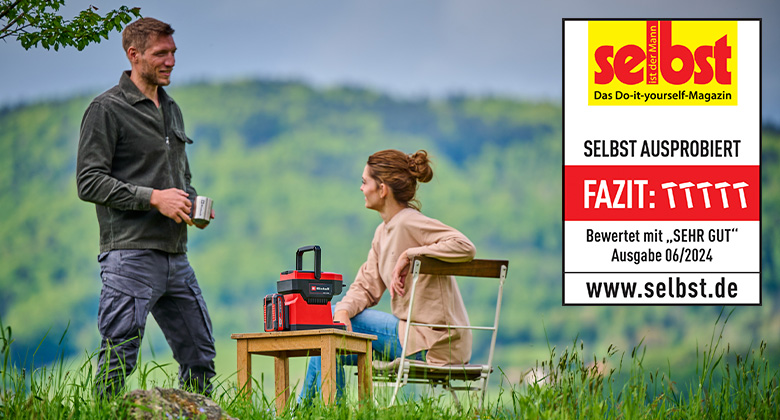 Two people sit outdoors with an Einhell cordless coffee maker on a table, rated "Very Good" by "selbst ist der Mann" in issue 06/2024.