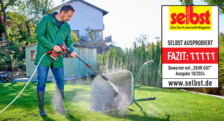 A man cleans a wheelbarrow in the garden with an Einhell cordless pressure washer, rated "Very Good" by "selbst ist der Mann" in issue 10/2024.