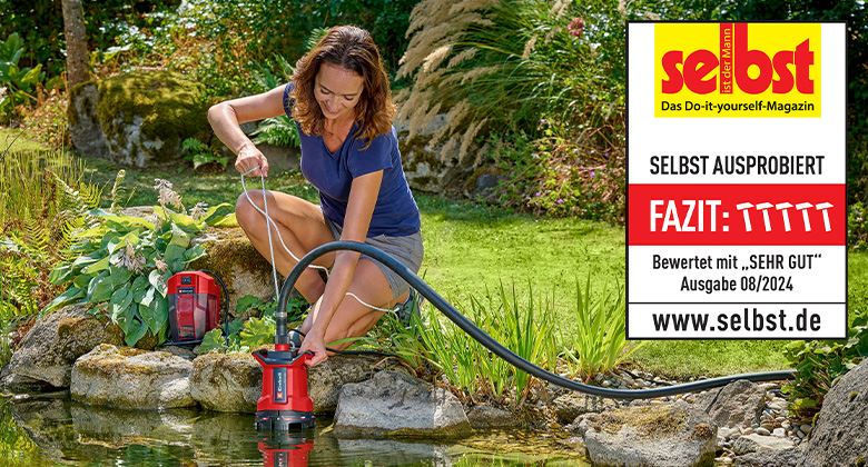 A woman uses an Einhell cordless dirt water pump at a garden pond, rated "Very Good" by "selbst ist der Mann" in issue 08/2024.