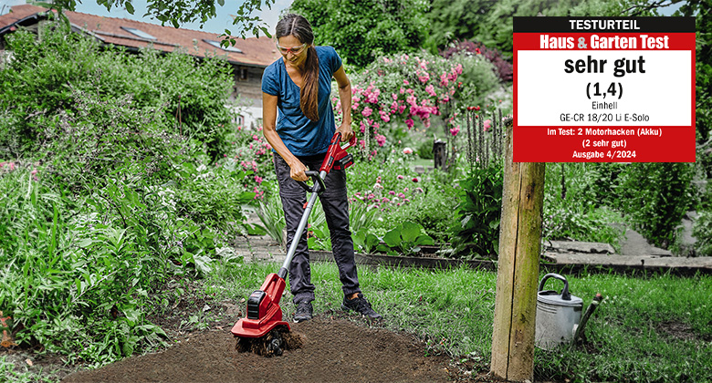 Eine Frau benutzt eine Einhell Akku-Bodenhacke im Garten, bewertet mit "Sehr Gut" (1,4) im "Haus & Garten Test," Ausgabe 04/2024.