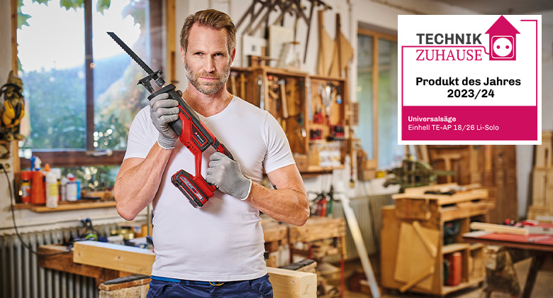 A man holds an Einhell cordless all purpose saw in a workshop, awarded as "Product of the Year 2023/24" by "Technik zu Hause."