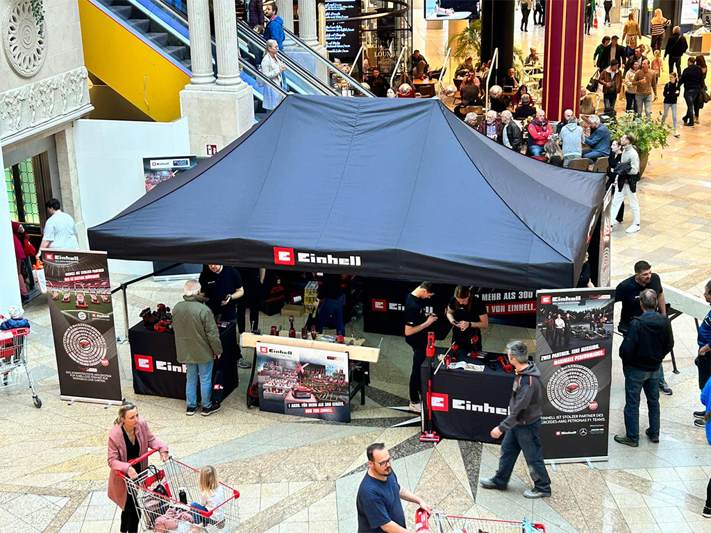 Einhell booth inside a shopping mall, showcasing tools and products with visitors exploring the displays.