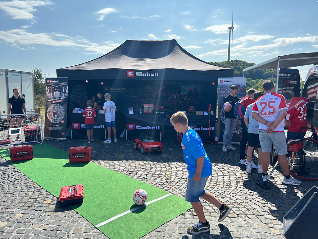 Einhell promotional booth outdoors with children and adults engaging in a soccer activity.