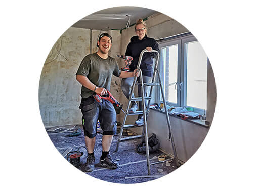 Woman on ladder and man with saw in hand from the homemaking project