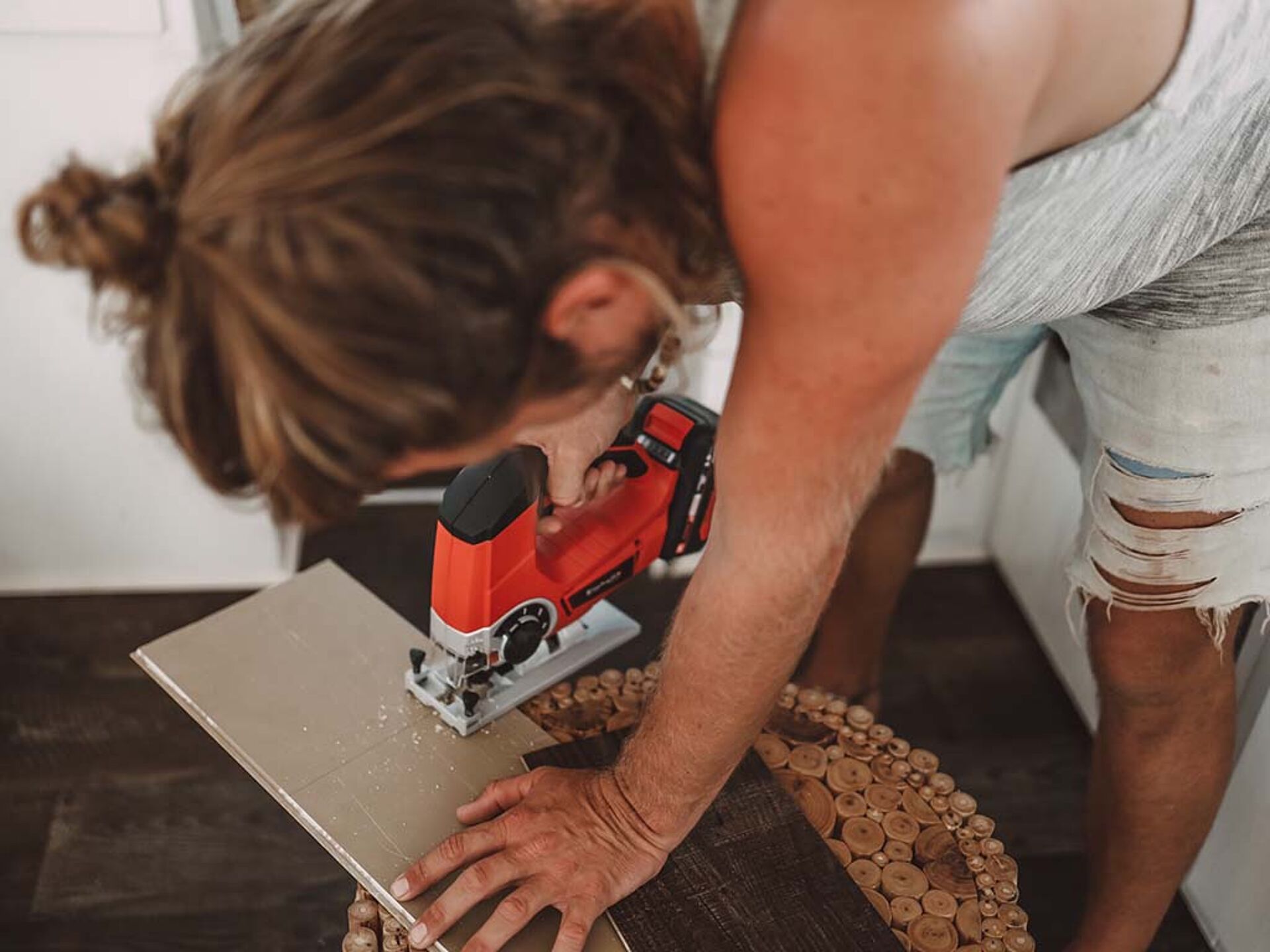 a woman cuts a board with a jigsaw