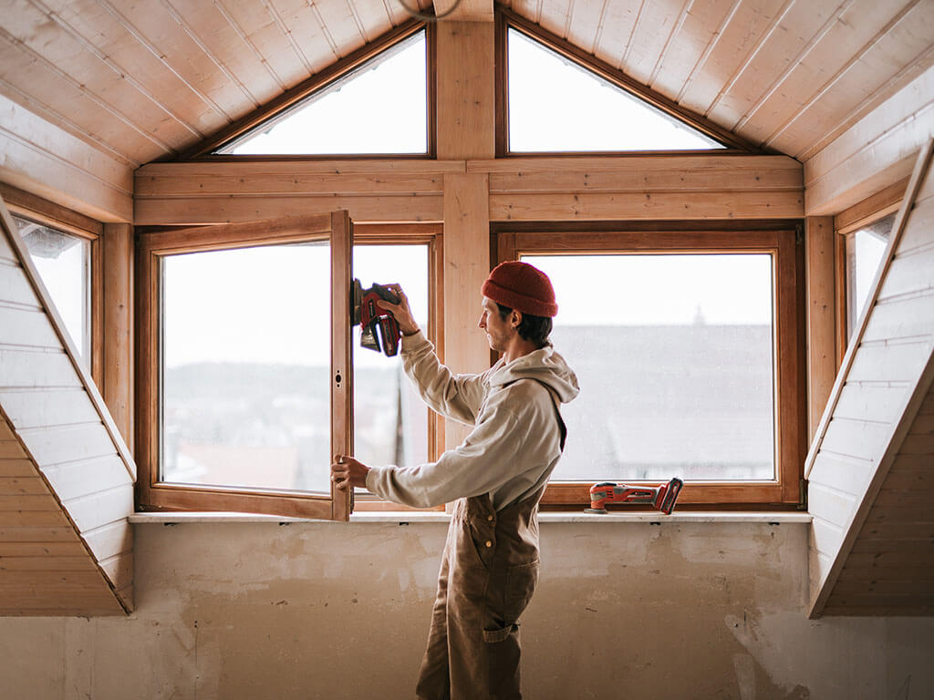 man sands a window frame