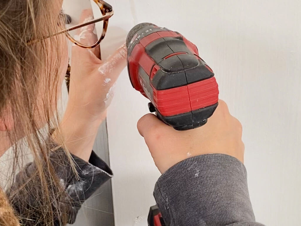 woman drills hole in wall