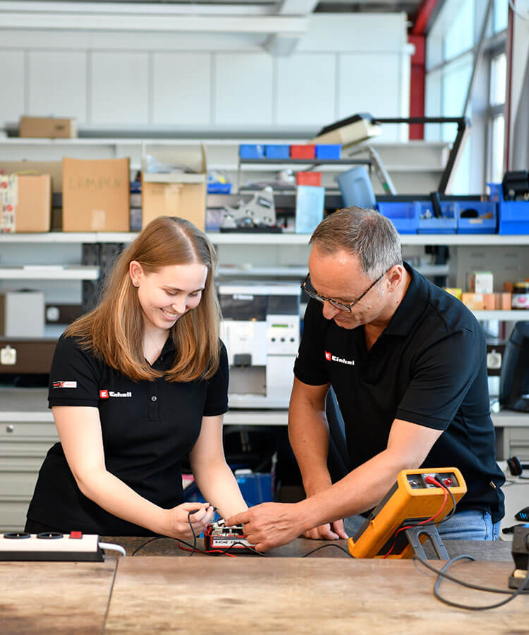 a woman and a man measure the current of a battery