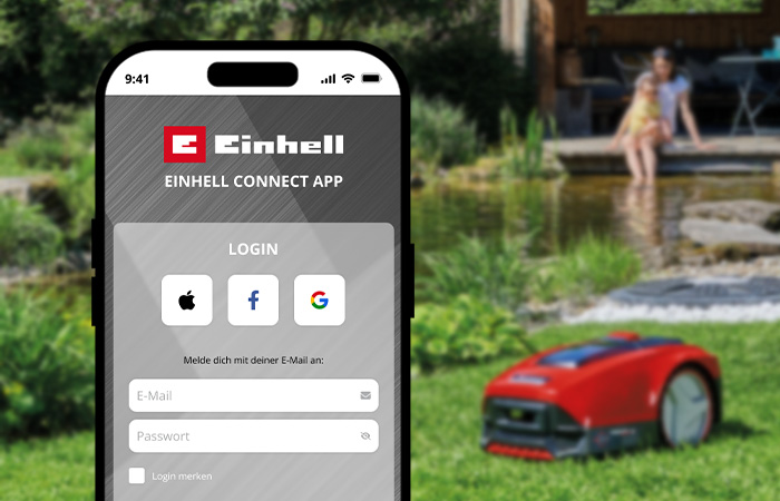 Ein Smartphone zeigt den Login-Bildschirm der Einhell-Connect-App vor einem Gartenhintergrund mit einem Mähroboter.